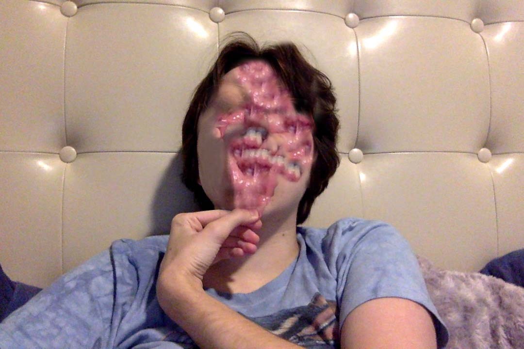 Webcam photo of me sitting on my bed pulling my lip down, but it's been photoshopped so that my inner lip is covering a lot of my face, making it look gory
