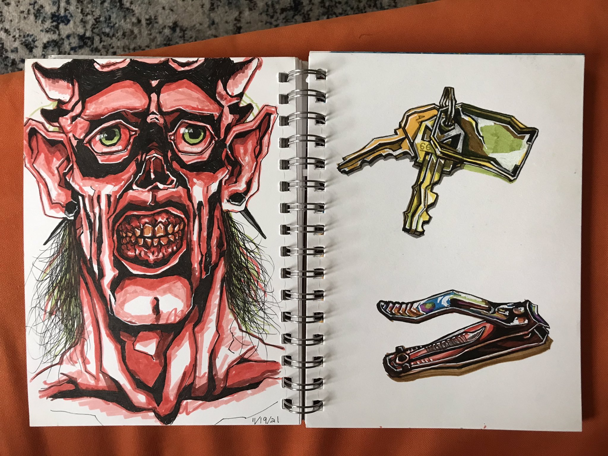 Photo of two sketchbook pages: one shows a red demon, the other shows drawings of keys and nail clippers
