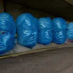 AI generated image of a line of heads wrapped in blue plastic under an overpass