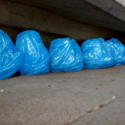 AI generated image of a line of heads wrapped in blue plastic under an overpass